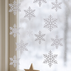 Fensterdeko mit Schneeflocken aus Papier oder Holz