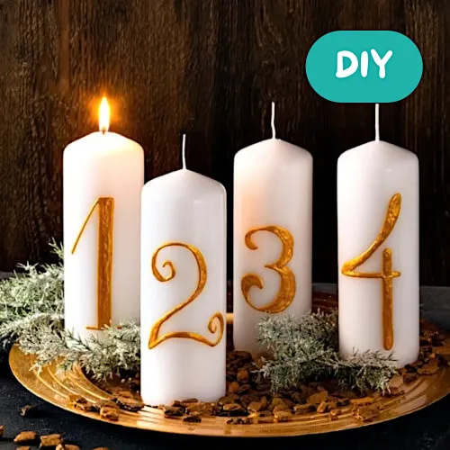 Vier weiße Adventskerzen mit goldenen Zahlen 1, 2, 3 und 4 auf einer dekorativen Unterlage, gestaltet als festliche Adventsdekoration.