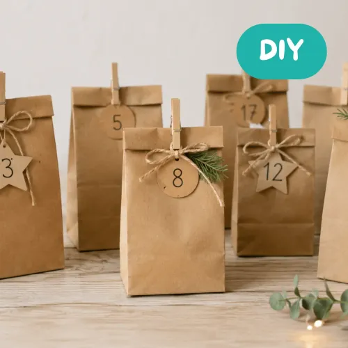 efüllte Kraftpapiertüten mit Adventskalenderzahlen, verschlossen und auf einem Bord aufgestellt.